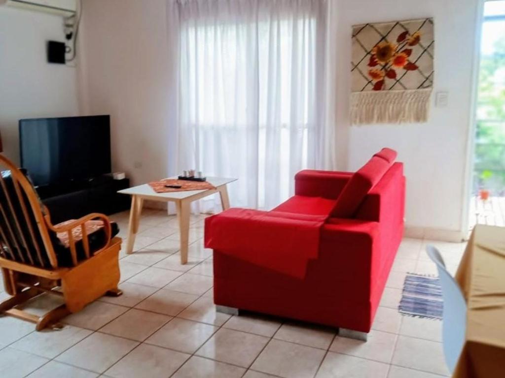 Una sala de estar con una silla roja y una mesa. en El Portal, en Posadas