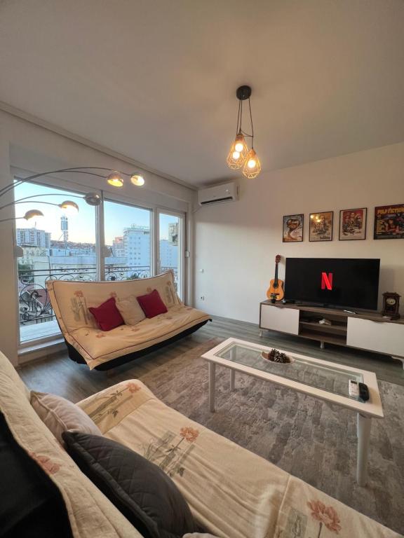 salon z kanapą i telewizorem w obiekcie Sunset Apartment w Prisztinie