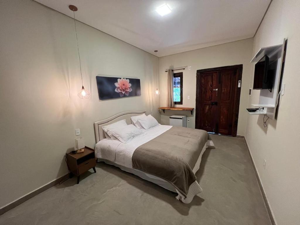 a bedroom with a bed and a flat screen tv at Pousada Karandá SerraNegra in Lindóia