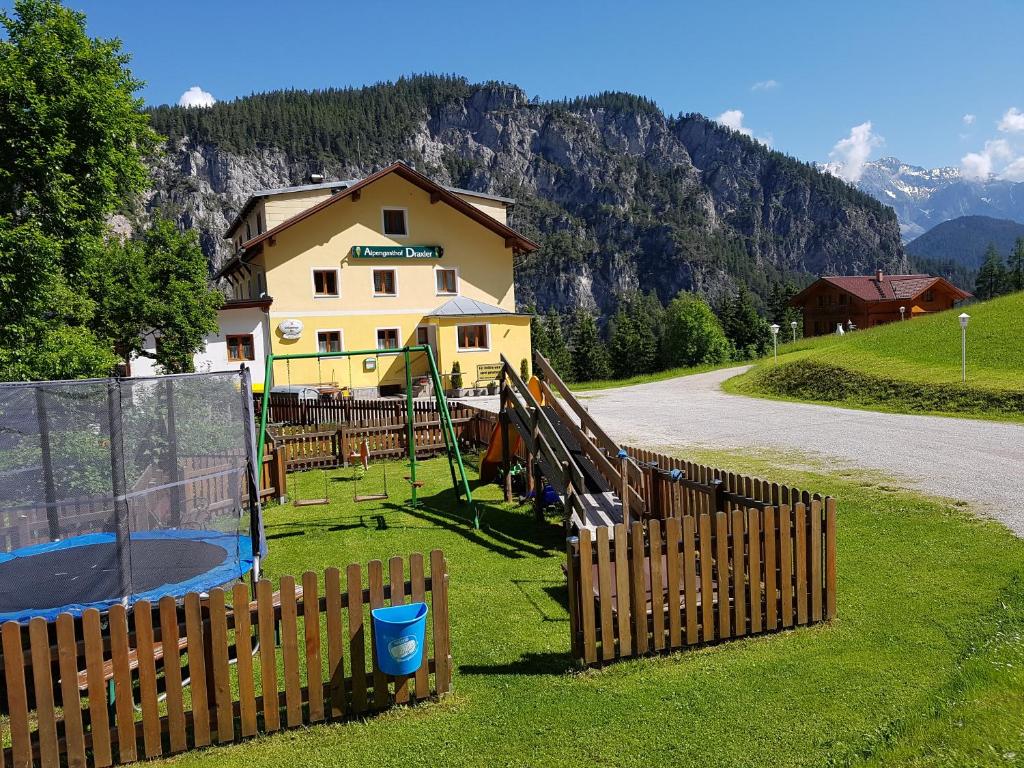 a house with a fence and a playground in the grass at Alpengasthof Draxler in Forstau