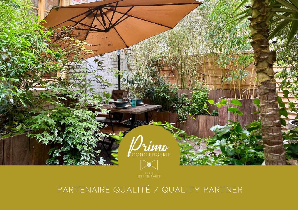 a garden with a table and an umbrella at LE JOSÉPHINE - Havre de paix proche Paris in Montreuil