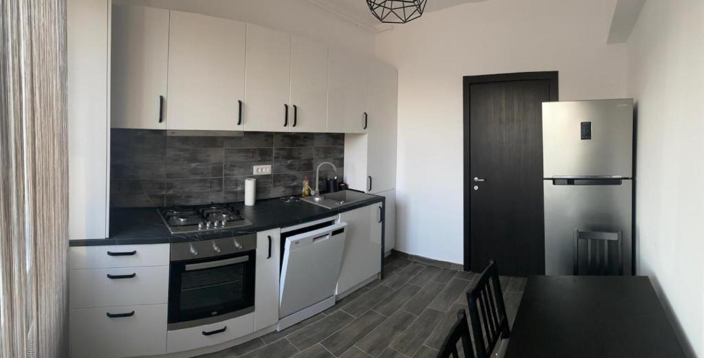 a kitchen with white cabinets and a stainless steel refrigerator at Zodian Residence Bucharest in Popeşti-Leordeni