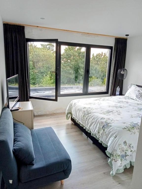 a bedroom with a bed and a couch and windows at Tomorrowlandhome Boom in Boom