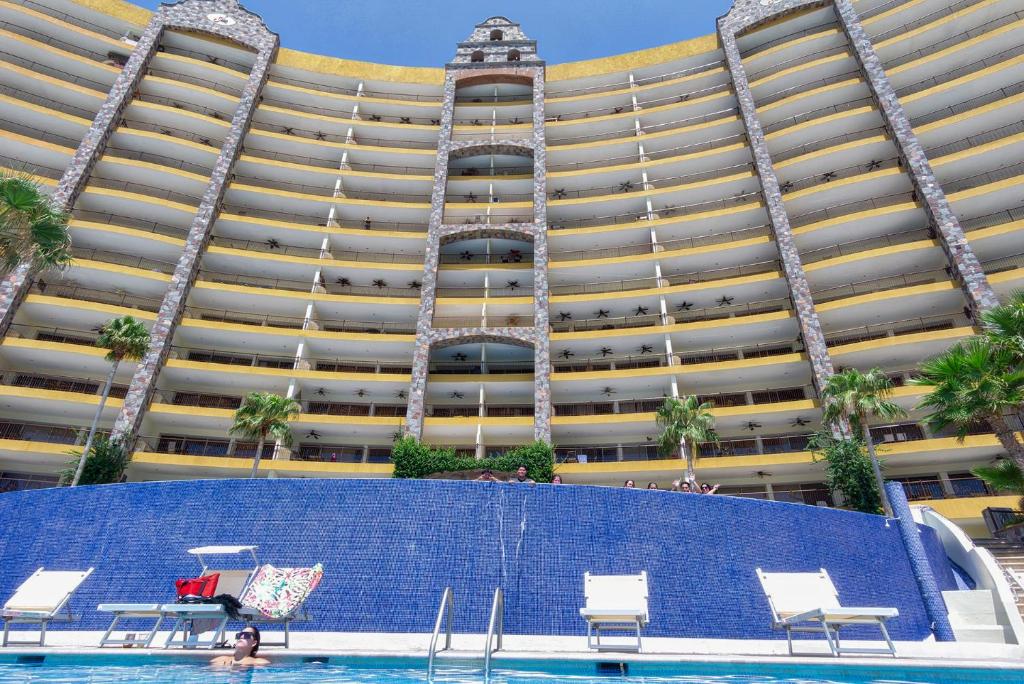 a large building with a pool in front of it at Vacationer's Dream Getaway Ocean Front Condo in Puerto Peñasco