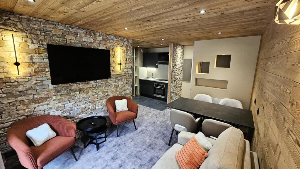 un salon avec une télévision sur un mur en briques dans l'établissement Résidence Le Thabor - maeva Home - Appartement 2 pièces 6 personnes - Sélection MAE-2784, à Le Désert