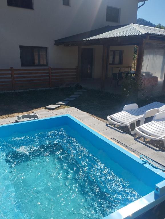 科利比塔Briza de Munte的一个有两把椅子的游泳池和一栋房子