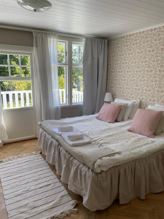 a bedroom with a large bed with pink pillows at Pensionat Haga Öland in Löttorp