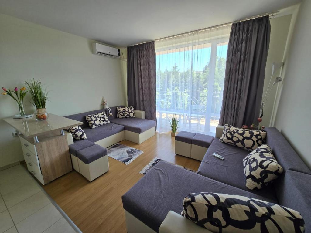 a living room with blue couches and a large window at Orchid Fort Garden in Sunny Beach