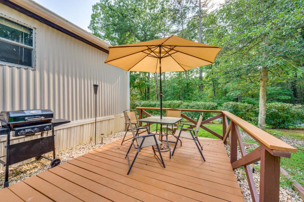 una terraza de madera con mesa y sombrilla en 3 Mi to Badin Lake Quiet New London Retreat, en Eldorado