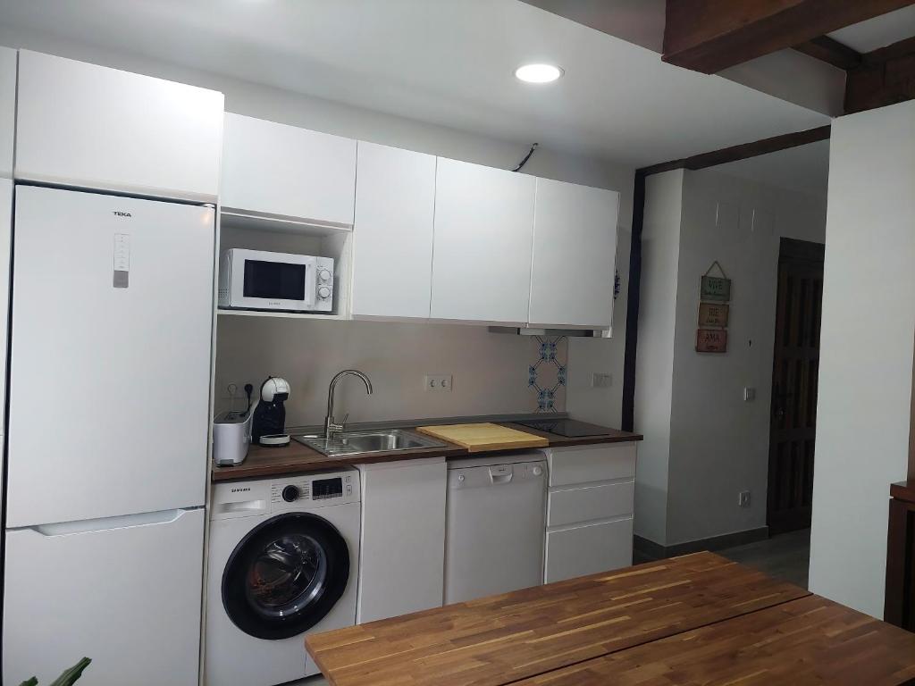 a kitchen with white cabinets and a washing machine at El Rincón de San Fermín in Zizur Mayor