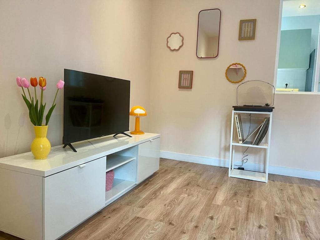 a living room with a television on a white cabinet at Maison avec terrasse et jardin in Avallon
