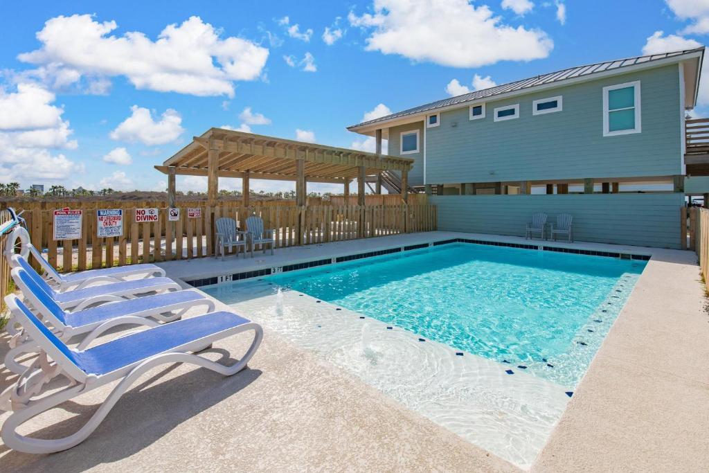 une piscine avec deux chaises et une maison dans l'établissement Cinema Shores – A Movie-Themed Beachfront Escape!, à Mustang Beach