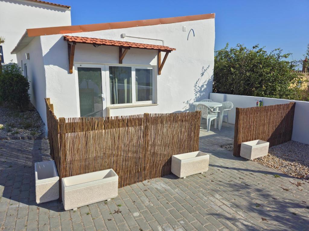 a small white house with a wooden fence at Apartamentos dos Mangues in São Martinho do Porto