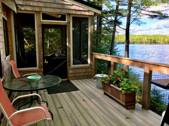 a screened in porch of a house with a table and chairs at Lakefront Cottage by Country House Escapes in Lincolnville