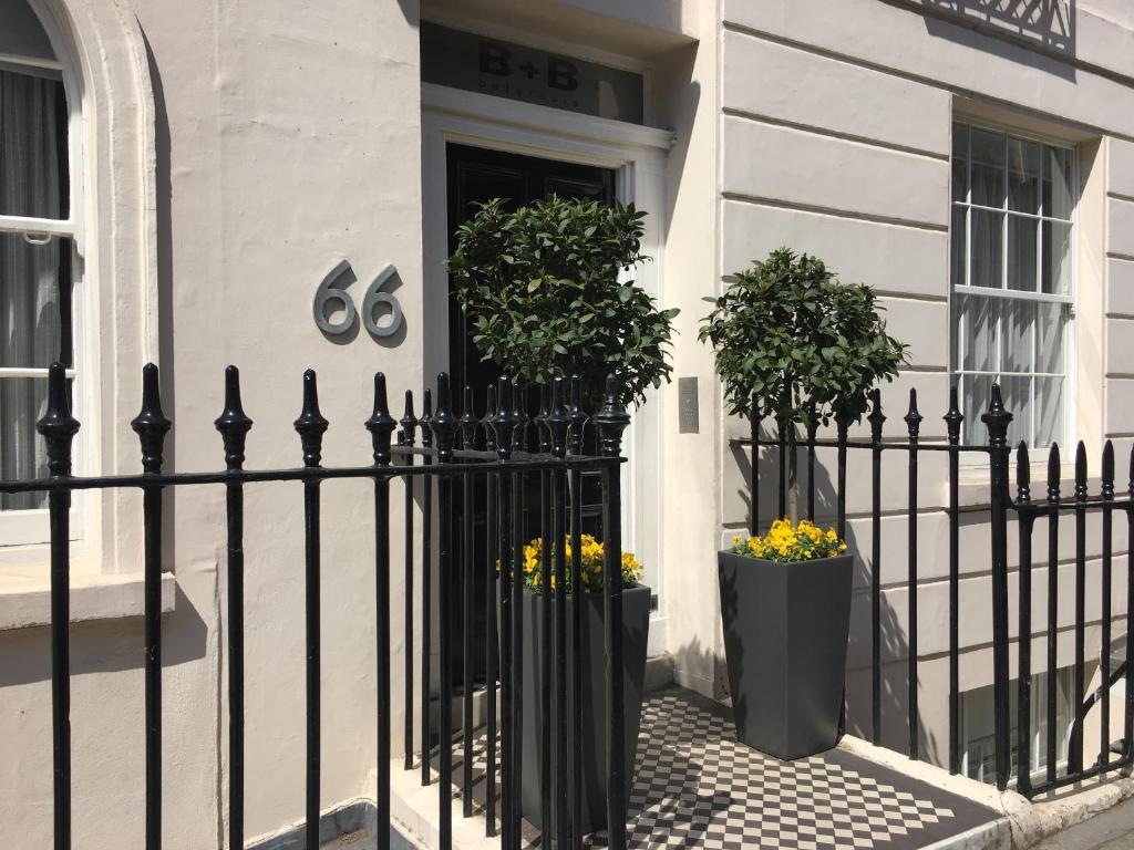 a black fence in front of a house with two plants at B&B Belgravia in London