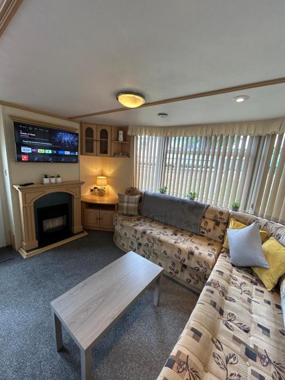 a living room with a couch and a tv at Bailey's Caravan Hire - Sealands Plot 1 - Wi-Fi - Dog Friendly in Ingoldmells