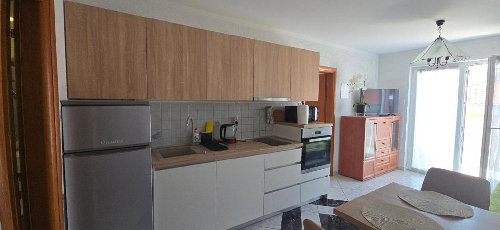 a kitchen with wooden cabinets and a stainless steel refrigerator at Apartment Albatross Ten in Novalja