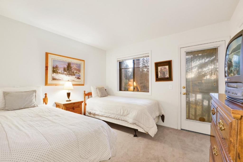 a white bedroom with two beds and a tv at Bear golf inn #1218 in Big Bear Lake
