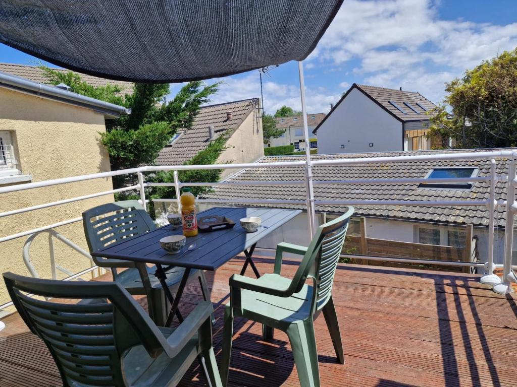una mesa y sillas en un balcón con sombrilla en Les Bleuets, en Saint Martin de Brehal