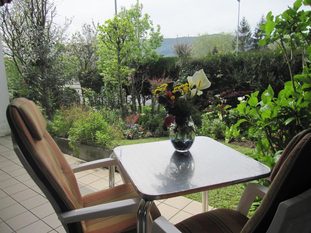 un jarrón de flores sentado en una mesa con dos sillas en Apartamento con Jardín, en Hendaya