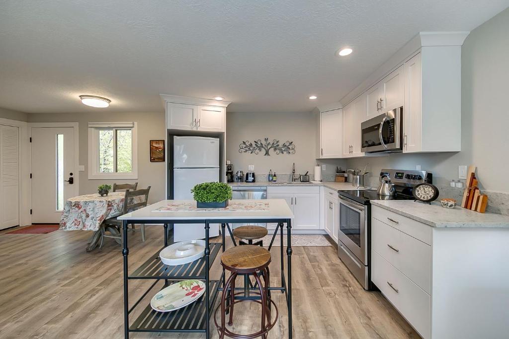a kitchen with white cabinets and a table with stools at It's The Melody! in Boise