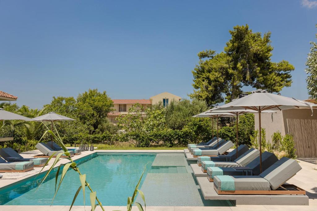 a swimming pool with lounge chairs and umbrellas at MARILIA VILLAS LASSI in Lassi