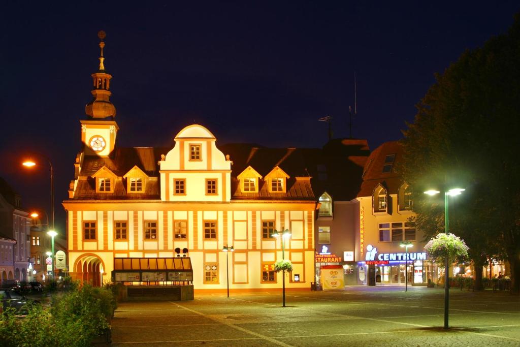 um grande edifício com uma torre de relógio à noite em IT Centrum Apartments em Vrchlabí