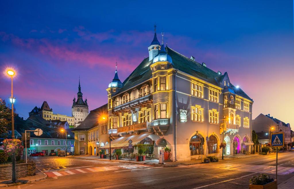 a large building on a city street at night at Heritage Boutique Hotel Sighisoara in Sighişoara