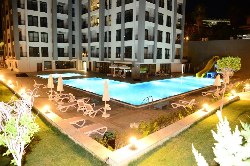 an outdoor swimming pool with tables and chairs and a building at Annabella Residence in Alanya