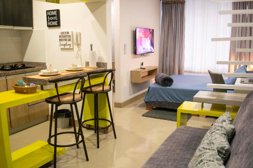 a room with a bed and a kitchen with yellow stools at Migar Alojamientos Prados Del Limonar in Cali