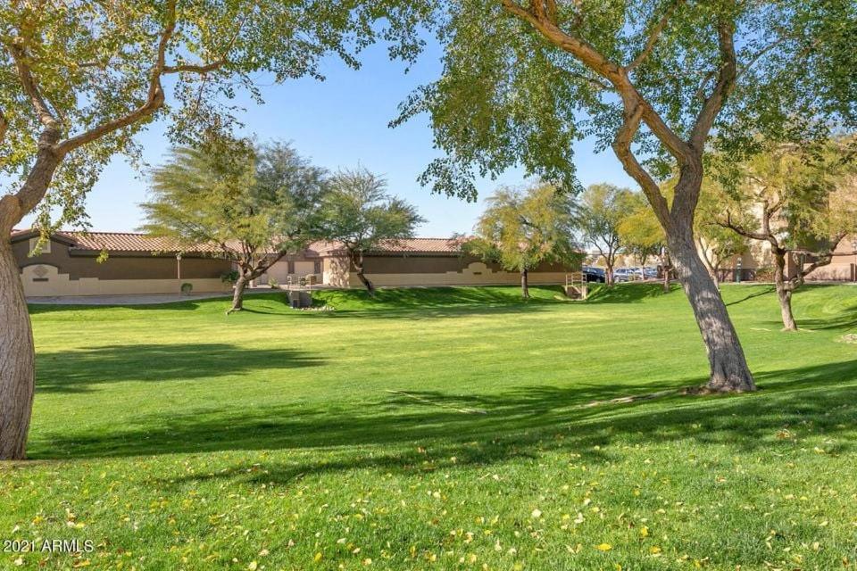a green yard with trees and a building at Ground Floor 2 BDR with Garage! Heated Comm Pool! in Mesa