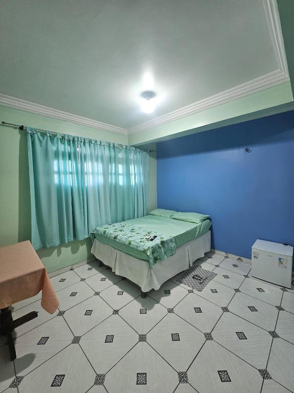 a bedroom with a bed in a room with blue walls at Hotel Marajoara Breves in Breves