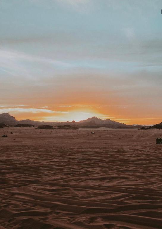 DisahにあるCamp jamal tourの山々を背景に砂漠に沈む夕日