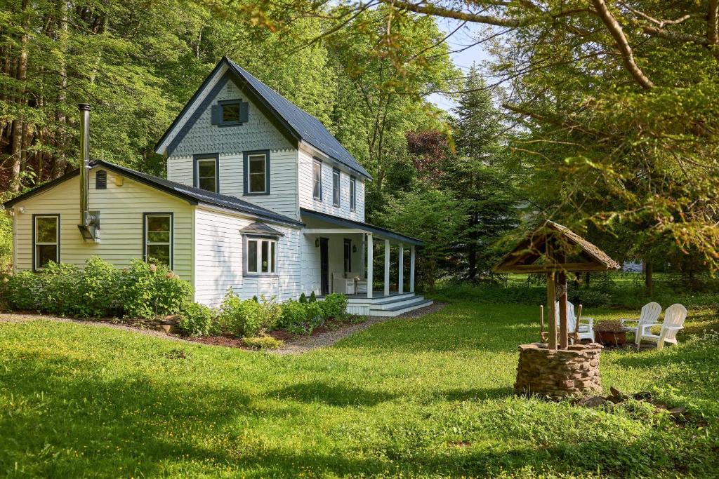 une petite maison blanche avec une cour dans l'établissement Historic Catskills Farmhouse Cottage by Belleayre, à Fleischmanns