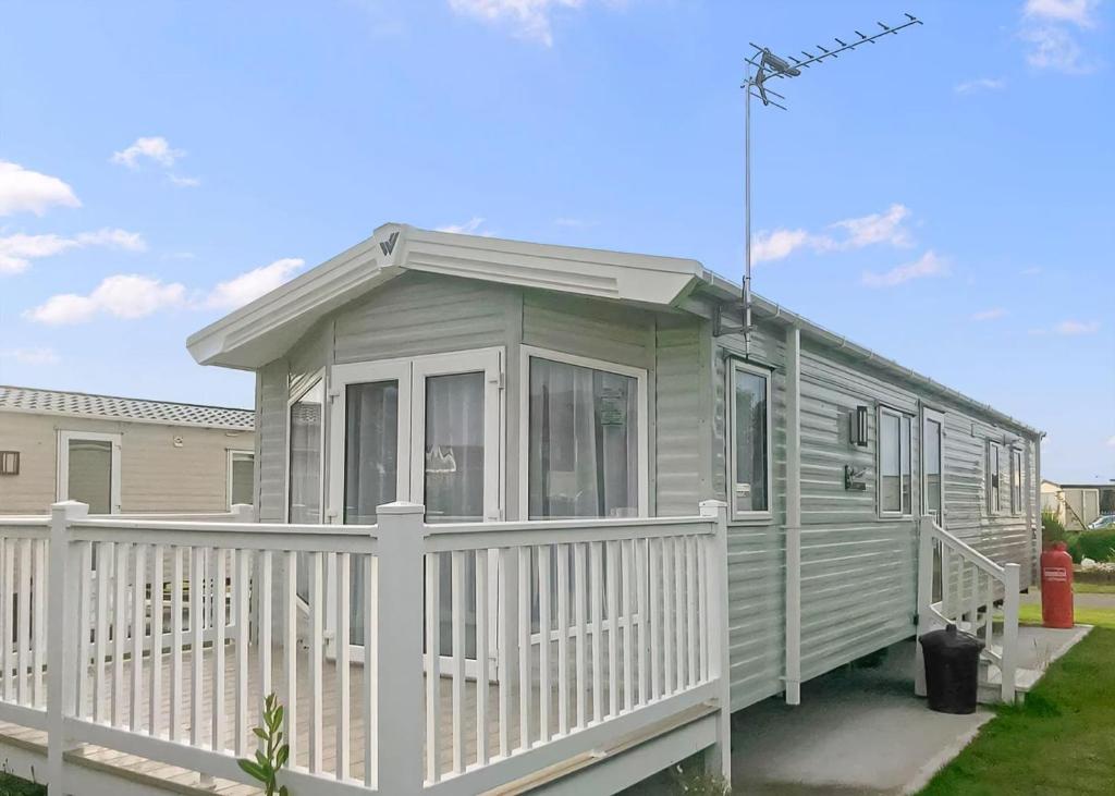 a green caravan with a white fence at Ty Gwyn Park in Abergele