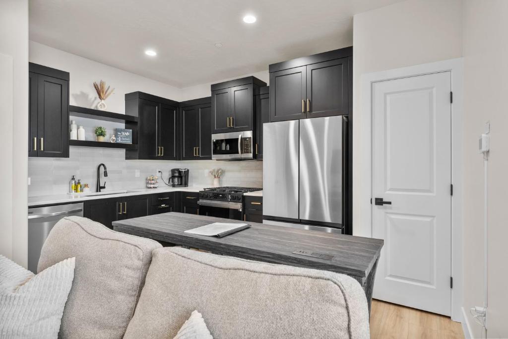 eine Küche mit schwarzen Schränken und einem Kühlschrank aus Edelstahl in der Unterkunft Modern Loft Getaway 25 Min to Zion, Walk to Food and Parks in Hurricane