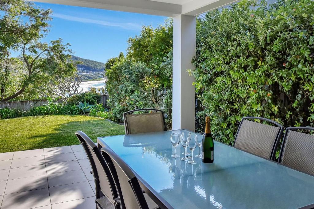 a table with wine glasses and a bottle of wine at Beach House 1 20 Pacific Drive in Fingal Bay