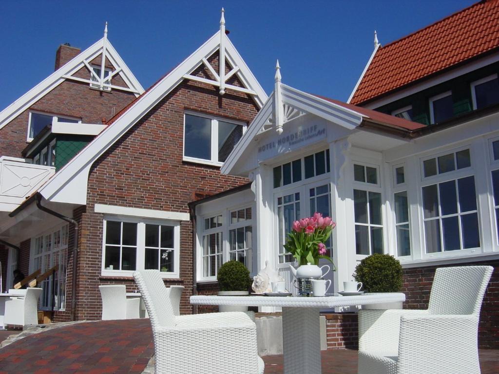 a table and chairs in front of a building at Hotel Norderriff in Langeoog