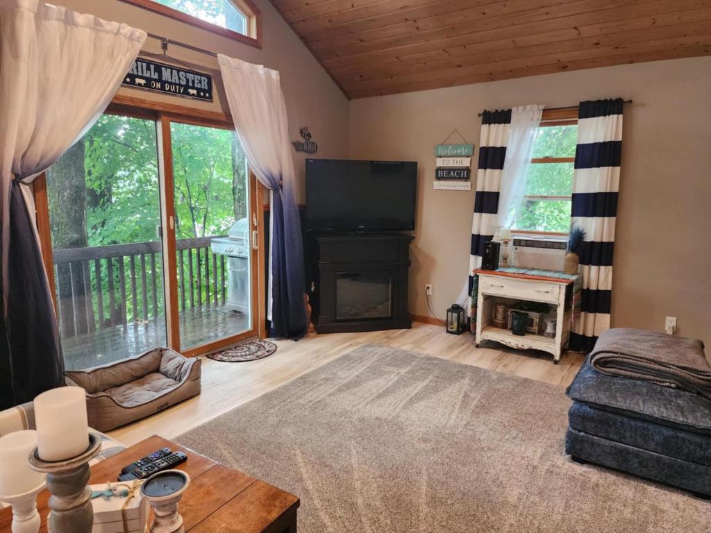 a living room with a fireplace and a television at Lake Front Cottage on Private All-Sports Lake. in Le Roy