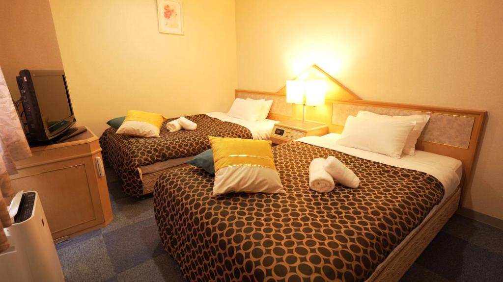 a hotel room with two beds and a television at 美祢グランドホテル in Mine