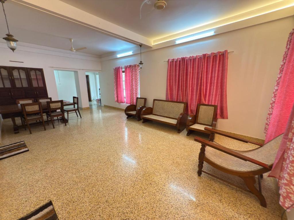a living room with chairs and tables and red curtains at RITU CAPITOL Homestay in Trivandrum