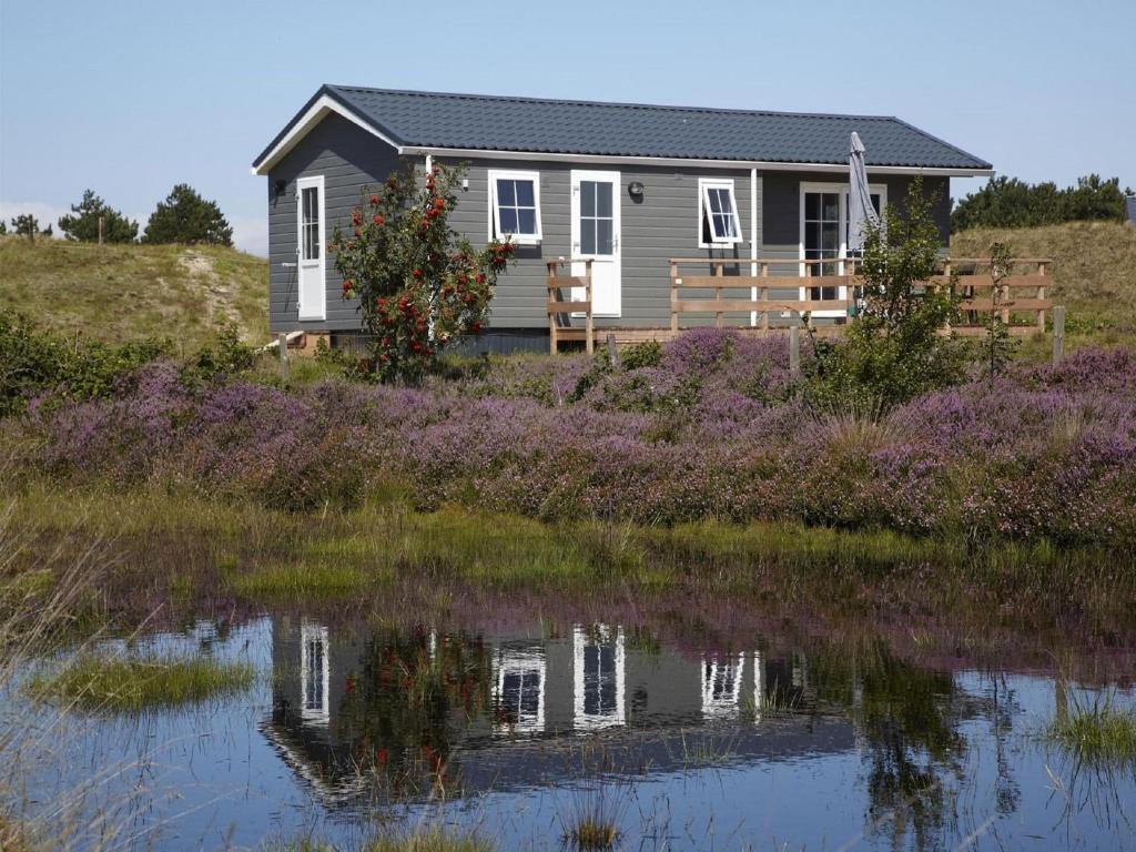 una casa en una colina al lado de un cuerpo de agua en Chalet in Texel with Private Sauna, en Den Hoorn