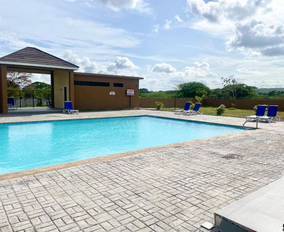 een zwembad met blauwe stoelen en een gebouw bij Resort Vibes Getaway - Colbeck Manor Old Harbour - Gated, pool, gym in Old Harbour