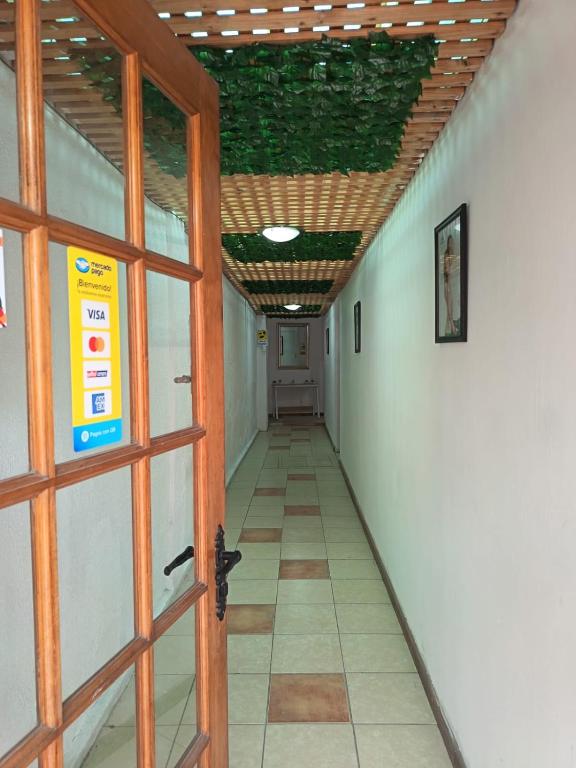 Un pasillo vacío con una habitación con techo verde. en Lodge Atacama Hostal, en Copiapó