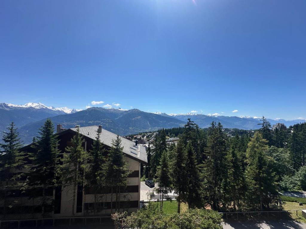 a building with trees and mountains in the background at Alpine Evasion - Crans Montana - Swiss Alps in Crans-Montana