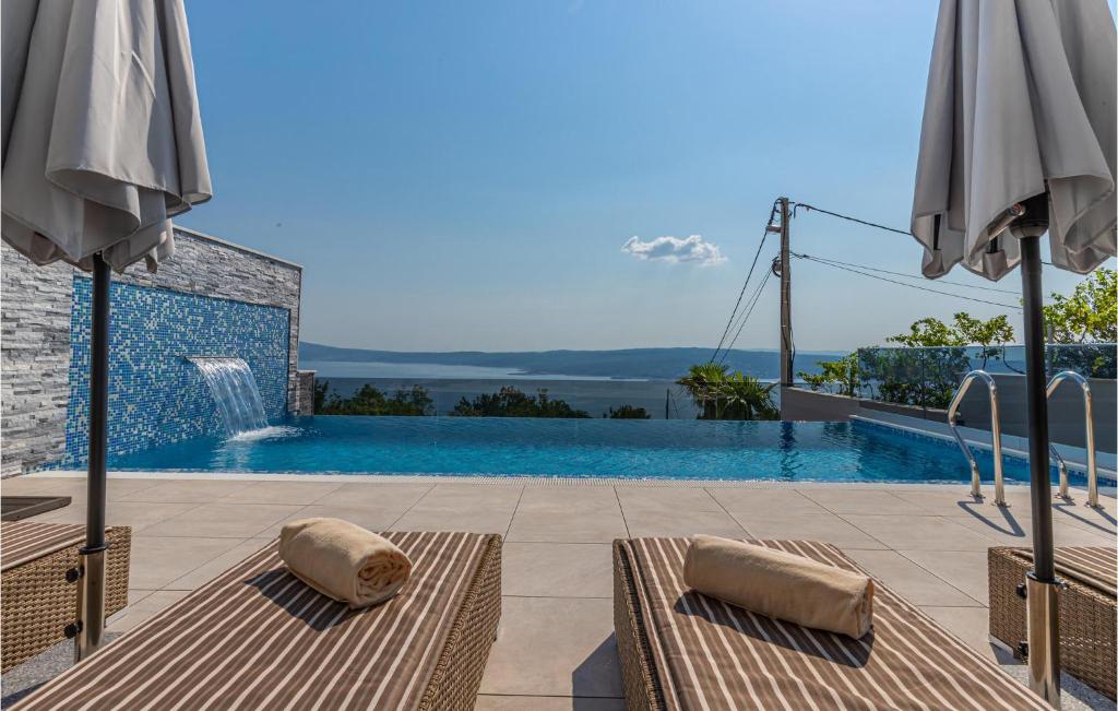 a swimming pool with two umbrellas on a patio at Awesome Home In Crikvenica With Sauna in Crikvenica