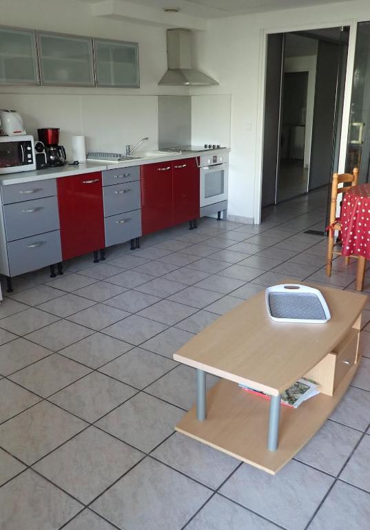 a kitchen with red cabinets and a table in it at Appartement spacieux de plain pied in Eugénie-les-Bains