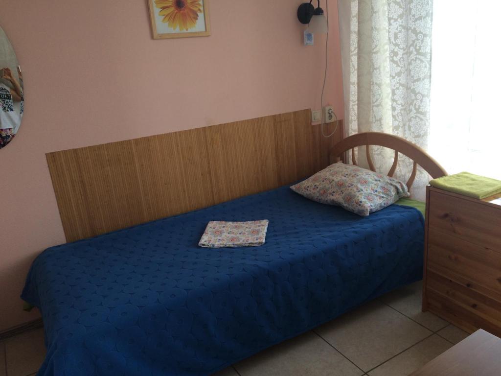 クシュチェフスカヤにあるMotel Sonyaのベッドルーム1室(青いベッド1台、木製ヘッドボード付)