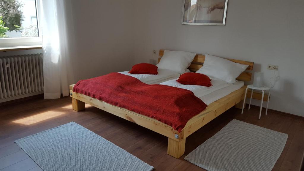Bett mit zwei roten Kissen auf einem Zimmer in der Unterkunft Ferienwohnung & Gästezimmer Rixner in Hilpoltstein