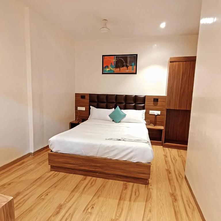 a bedroom with a bed with white sheets and wooden floors at Deluxe Residency Nr- Mumbai International Airport in Mumbai